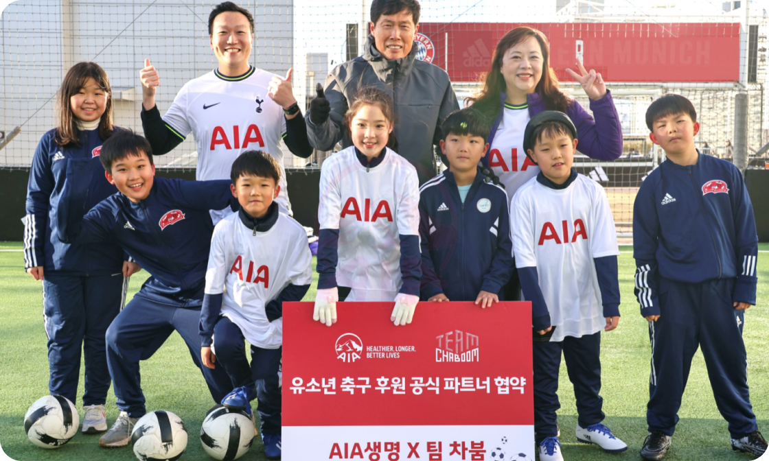 축구장에서 아이들과 기념사진을 찍고 있는 AIA생명 대표이사, 차범근 감독, AIA생명 마케팅 본부장